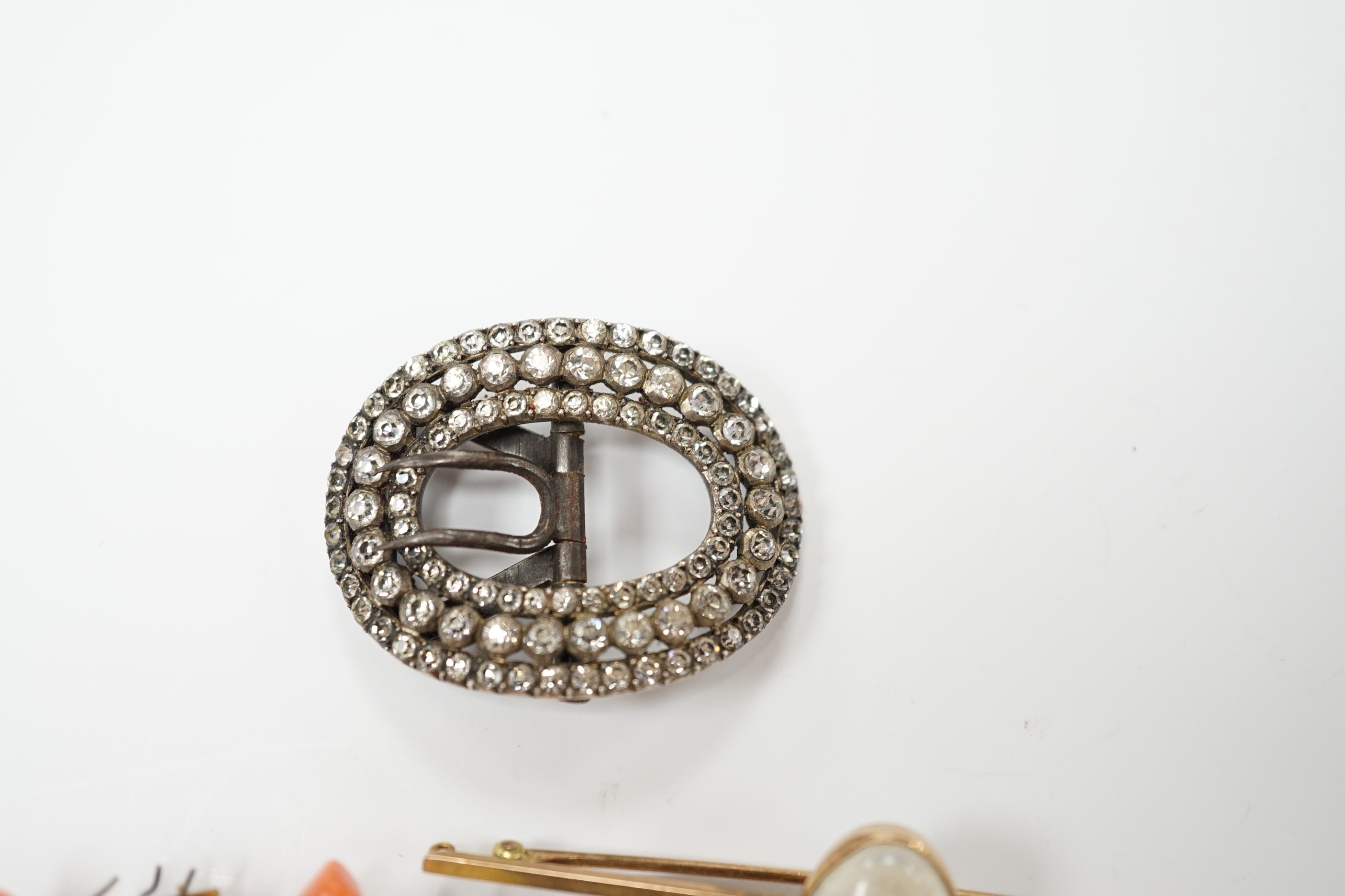 A 9ct and cabochon moonstone set bar brooch, 63mm, a coral and horn set bug stick pin and a paste set buckle.